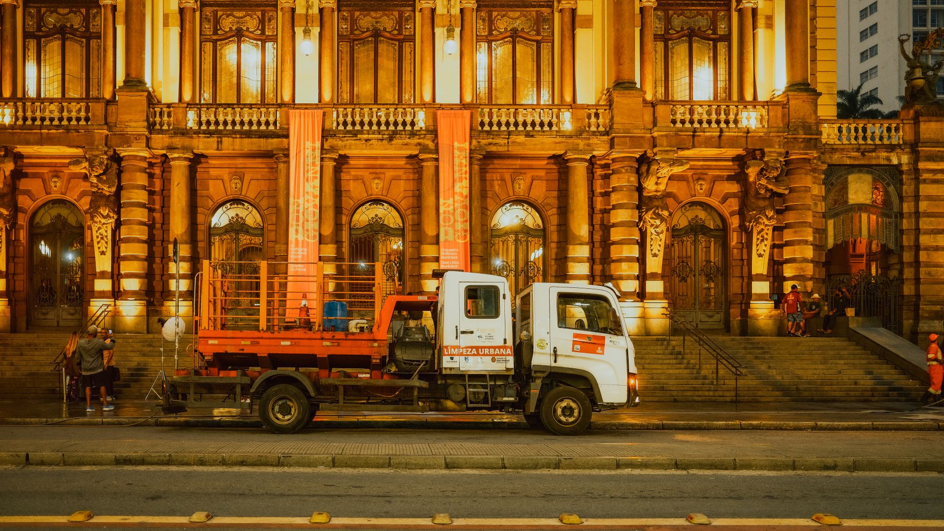 Front view of the Municipal Theatre in São Paulo, Brazil, illuminated at night with an urban cleaning truck parked in front.