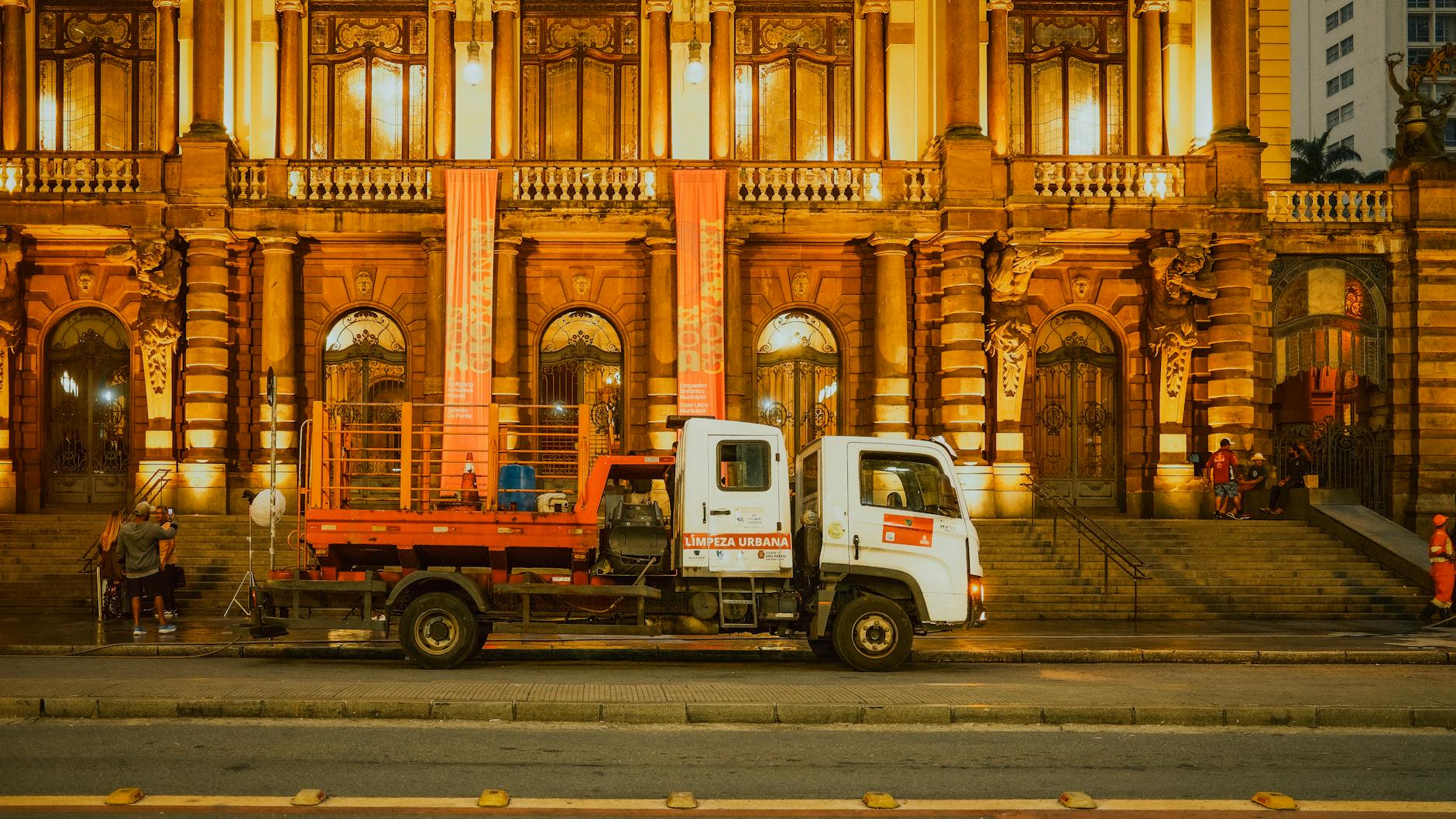 Front view of the Municipal Theatre in São Paulo, Brazil, illuminated at night with an urban cleaning truck parked in front.