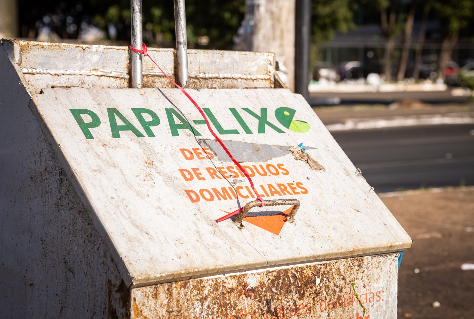 A weathered waste collection bin labeled Papa-Lix, located outdoors in an urban setting.