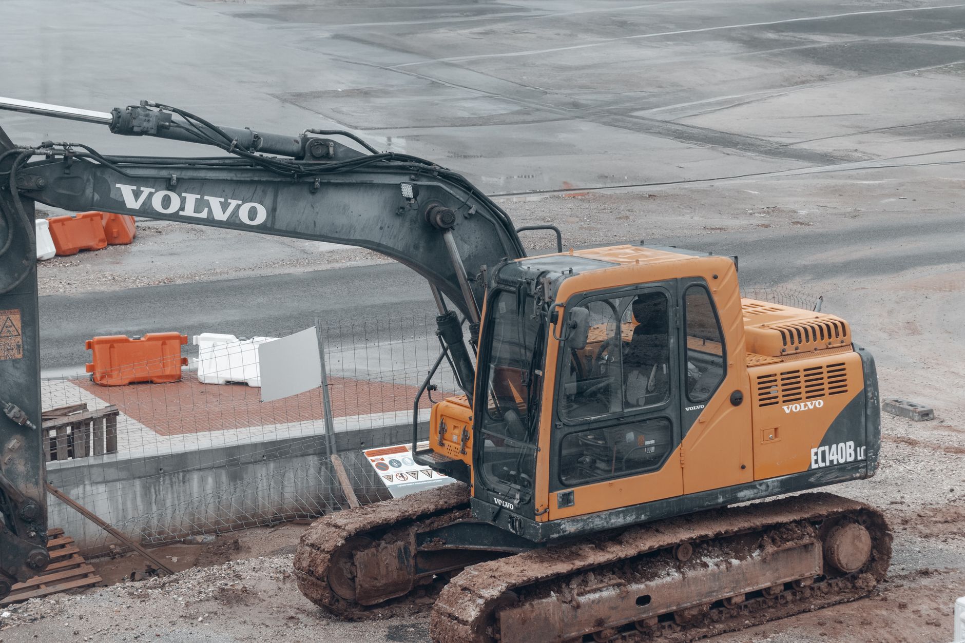 A yellow Volvo excavator at a construction site with muddy tracks.