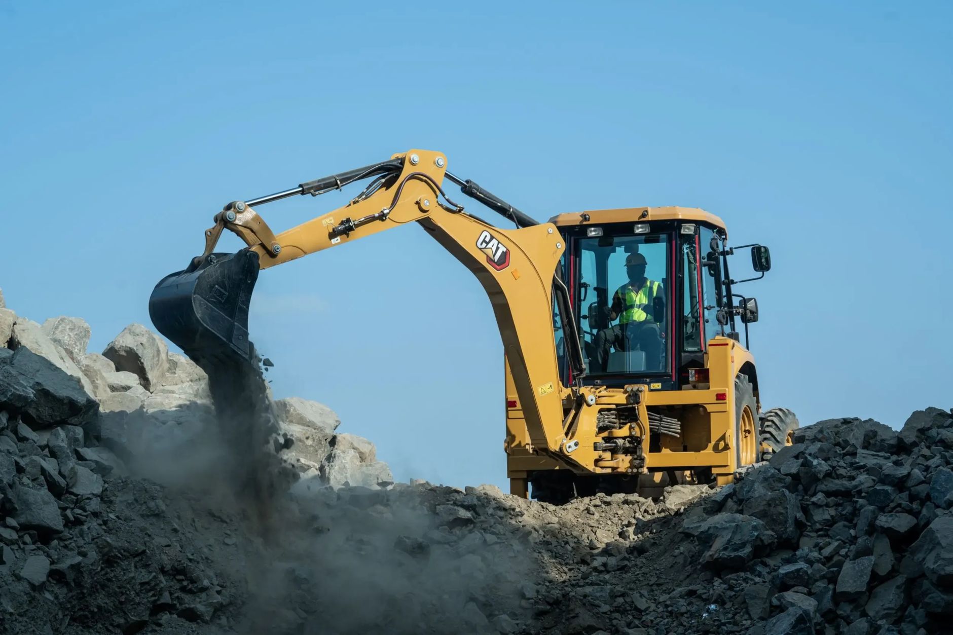 Heavy machinery operating at a construction site in India, moving rocks.