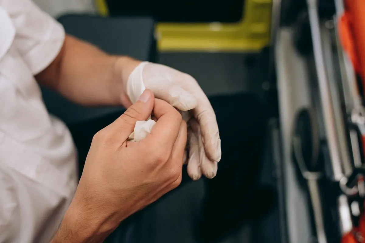 Close up of a paramedic donning gloves in an ambulance setting, highlighting emergency preparedness.